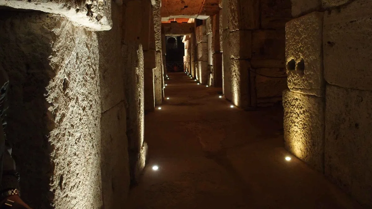 Group with a guide on the upper tier of the Colosseum looking down at the hypogeum on a Rome underground tour